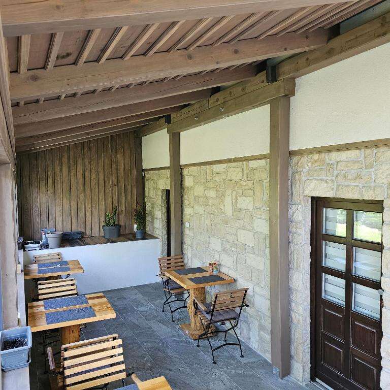 Covered stone terrace with wooden breakfast tables